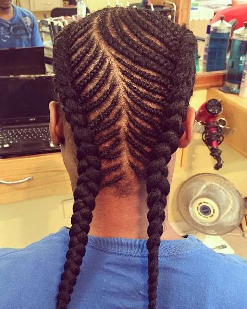 A picture of a guy with long hair braided into cornrows and french braids at a barbershop