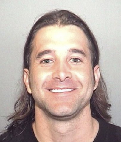 A criminal mugshot picture of Scott Stapp with his long hair in a slicked back hairstyle