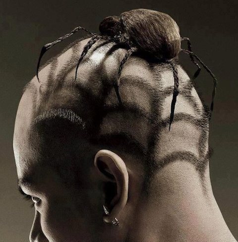 A photograph of a guy with a buzz cut haircut and a tarantula bun hairstyle on his head