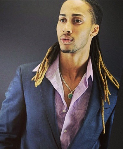 A professional photograph of a black man with long hair and a trendy blond dreadlocks hairstyle
