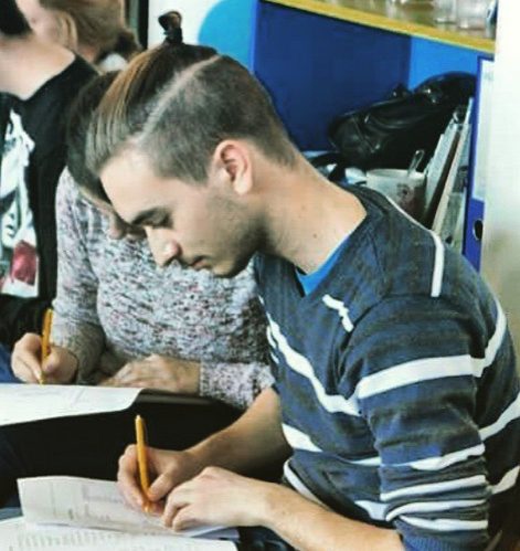 A young student boy with a topknot undercut haircut during one of his school classes