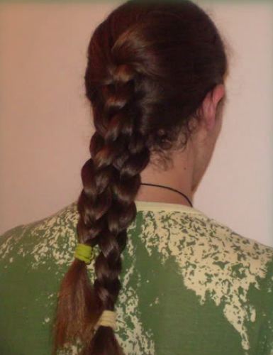An interesting picture of a long haired male with two French plaits as his long hairstyle dangles on his back