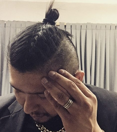 A picture of a Latino guy with a trendy man bun undercut hairstyle with braided long hair