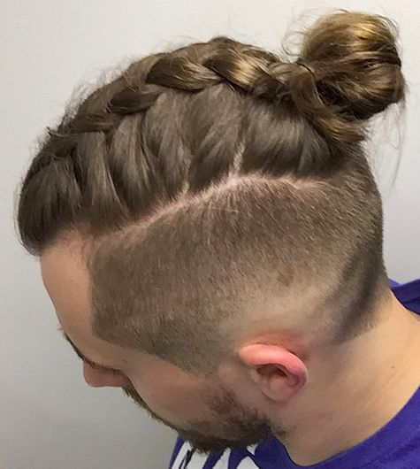 A barbershop picture of a guy with a man bun undercut hairstyle made up of braided locks of hair