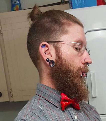 A selfie photograph of a hipster male with a top knot undercut hairstyle and a long beard