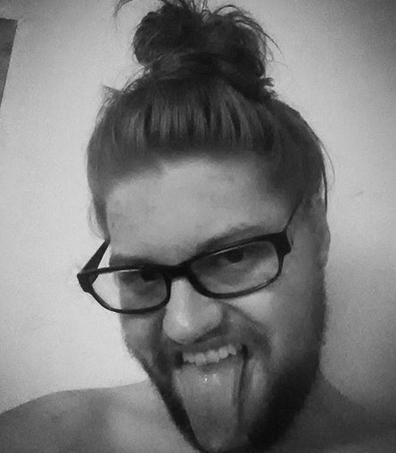 A photograph of an ugly nerdy guy with a manbun hairstyle and a hipster beard wearing glasses