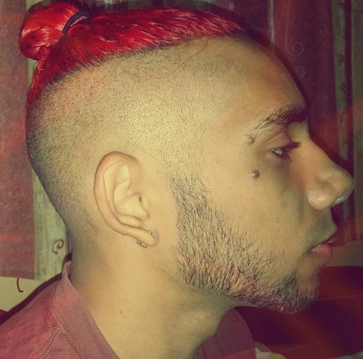 A side profile picture of a black male with red hair and a man bun undercut hairstyle complemented with a hipster beard