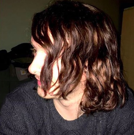 A picture of a skater boy with long wavy hair styled to the side with a high-shine water based pomade