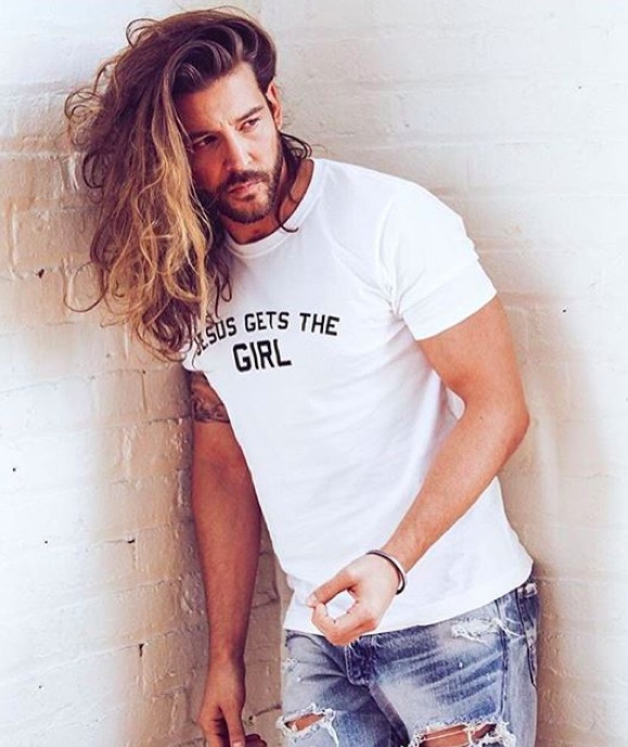 A photograph of a handsome male with an epic side part hairstyle for his long wavy hair
