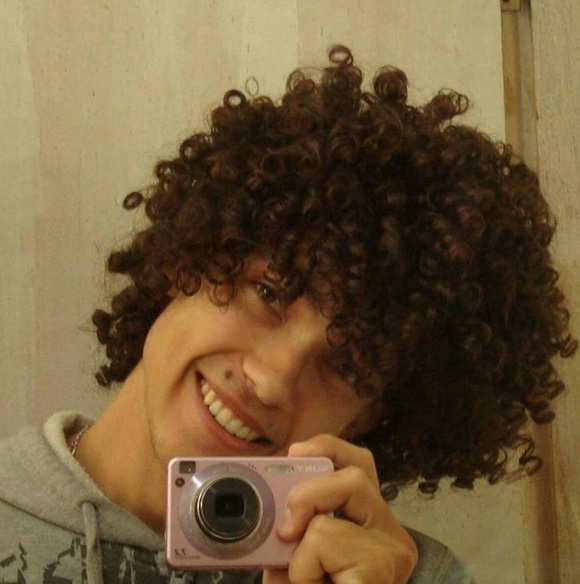 A photograph of a Brazilian young male with his curly hair styled as a Bob-cut hairstyle