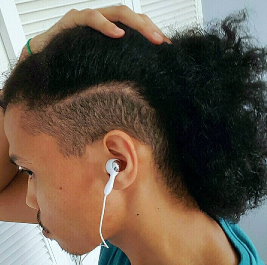 A photograph of a mulatto male with his long curly hair styled in an undercut haircut all across the sides and back of his head