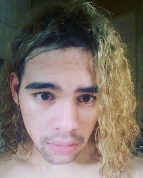 A photograph of long hair male with bleached curls that look damaged from getting a surfer hairstyle for too-many consecutive months