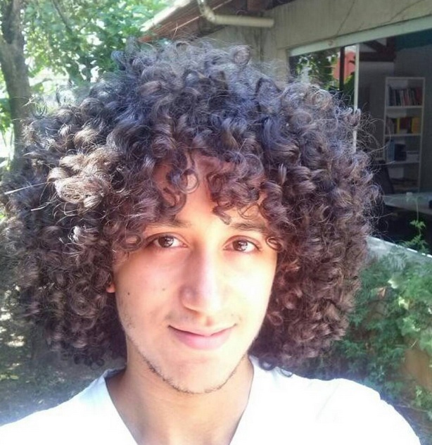 A photograph that shows how coiled curly hair looks like as the long-haired male in the photograph smiles for the camera