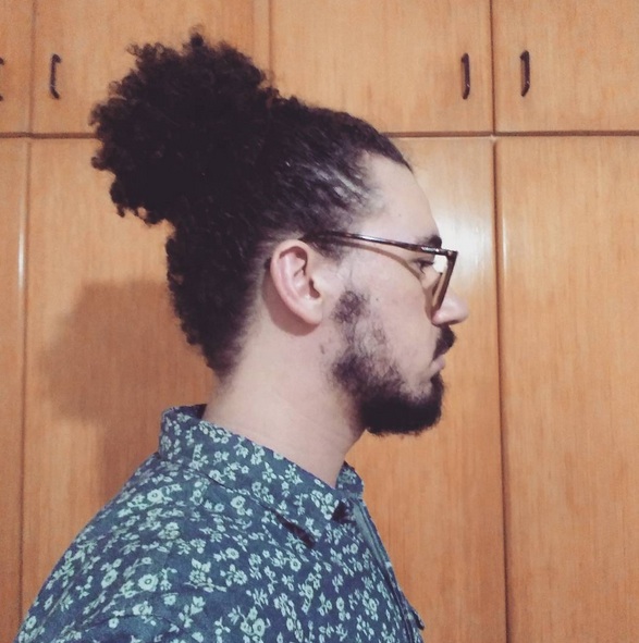 A picture of a Spanish guy with a man bun hairstyle and a tape haircut for his cool long curly hair