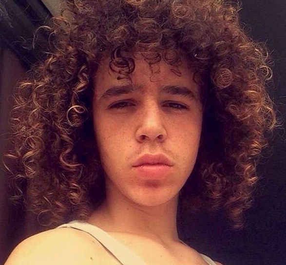 A picture of a twenty-year-old male of mixed-race heritage who has his long curls styled in a messy look