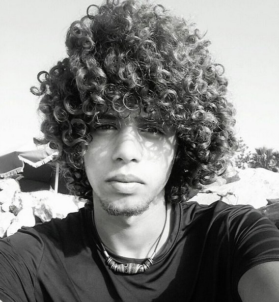 A picture of a young black guy with a long afro hairstyle that looks similar to the haircut of Jim Morrison in his youth