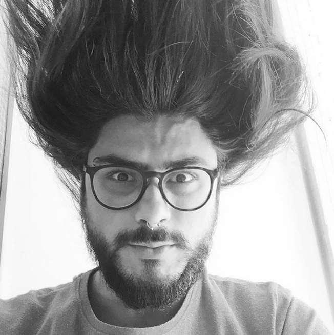 A photograph of a Skrillex-lookalike male with a Balbo beard style and very long hair that has been blown up with a hairdryer