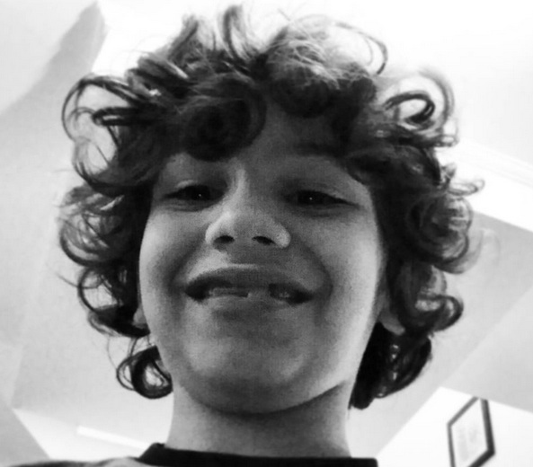 A photograph of a Puerto-Rican boy sporting his long wavy hair in a hairstyle similar to the one of Jim Morrison