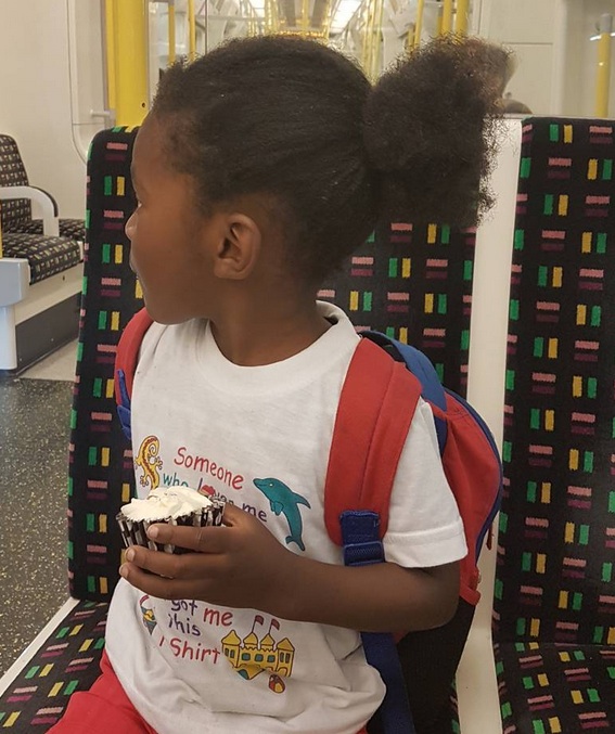 A photograph of a ten-year-old black boy sporting a man bun hairstyle for his long kinky curly hair