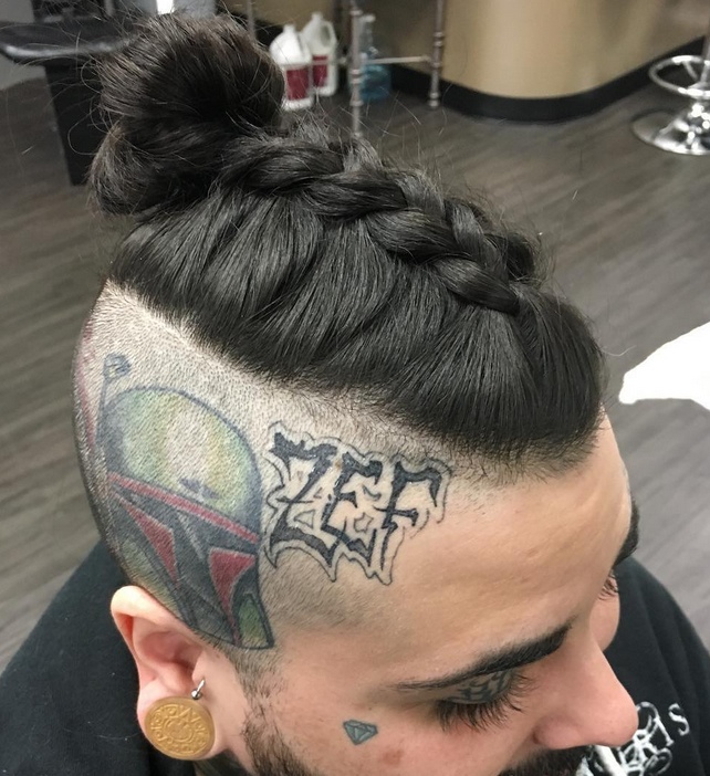 A barbershop photograph of a male hipster with his long hair trimmed as a man bun undercut and braided into one of the trendiest styles of 2017 which is known as the manbraid hairstyle