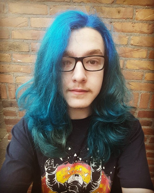 A photograph of a New York hipster dude with his long hair in a side part hairstyle and colored blue as per the new 2017 hairstyle trend