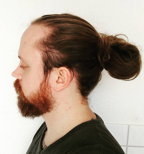 A photograph of a long-haired guy sporting a new trendy version of the man bun hairstyle for 2017 known as the low manbun