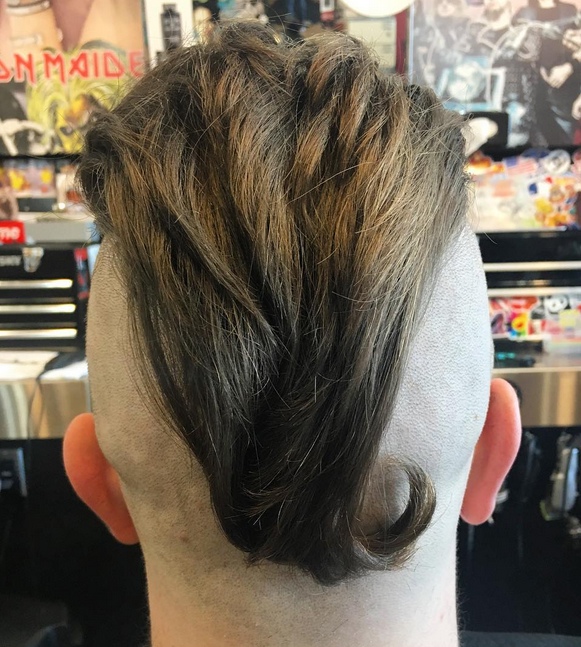 An epic barbershop photograph of a young American male sporting a slicked back undercut hairstyle for his hair that has been shaved into what is known as an undershave hairstyle
