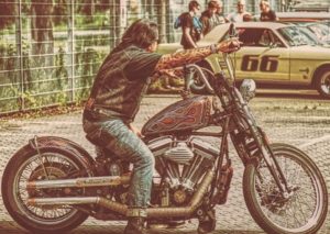 A photograph of a long hair guy riding an old Harley motorcycle